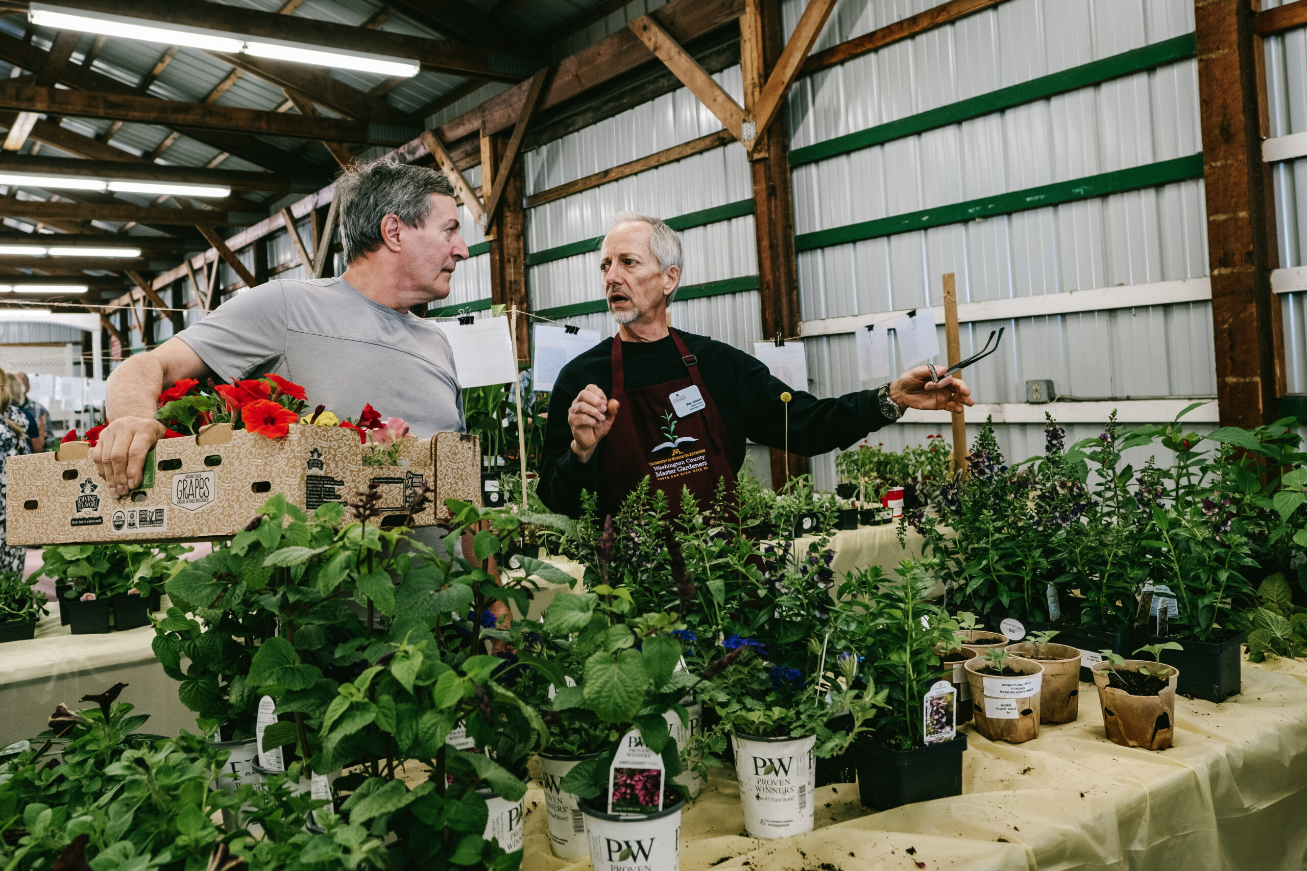 A master gardener volunteer discusses plants with a customer at the plant sale.