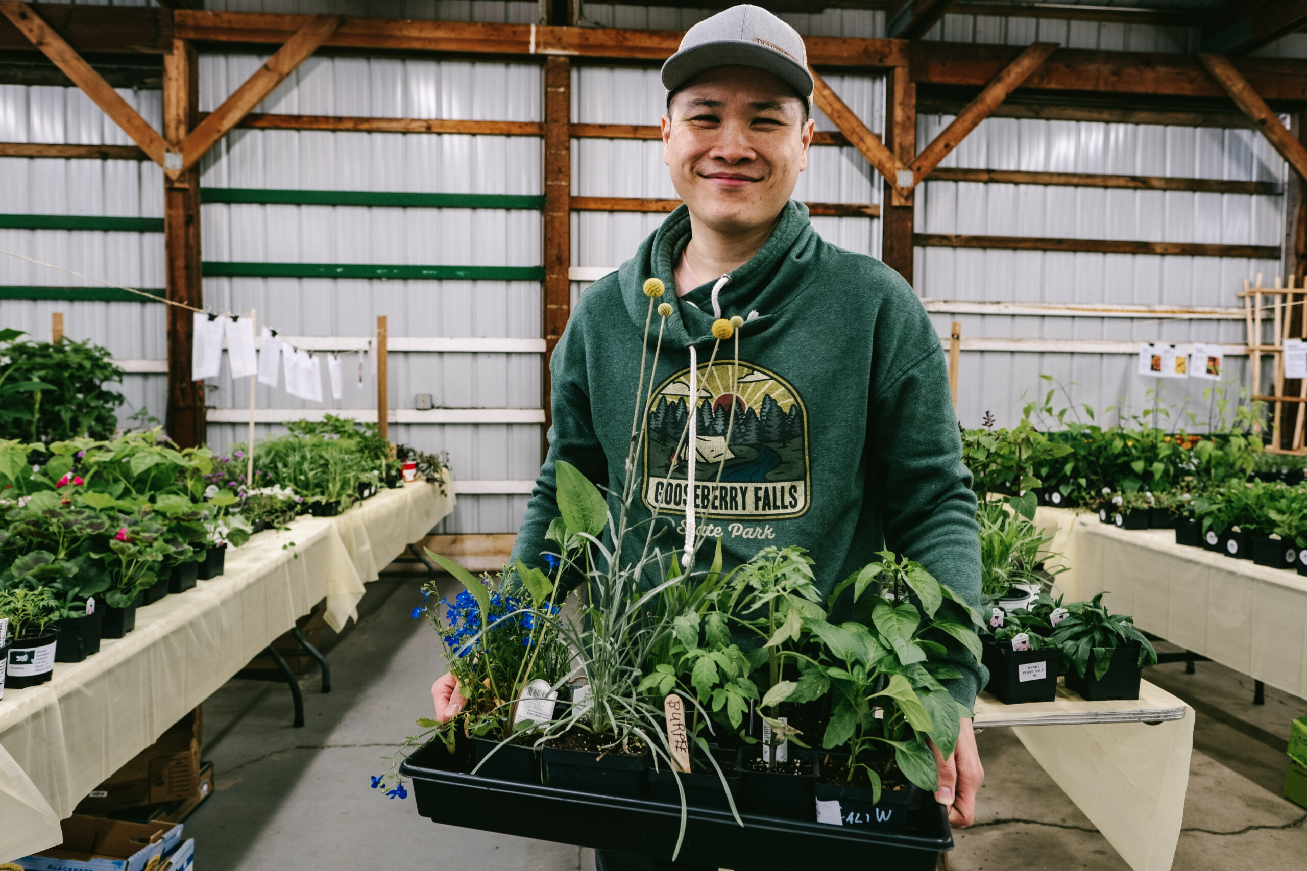 A happy customer with a variety of plants at the master gardener plant sale.