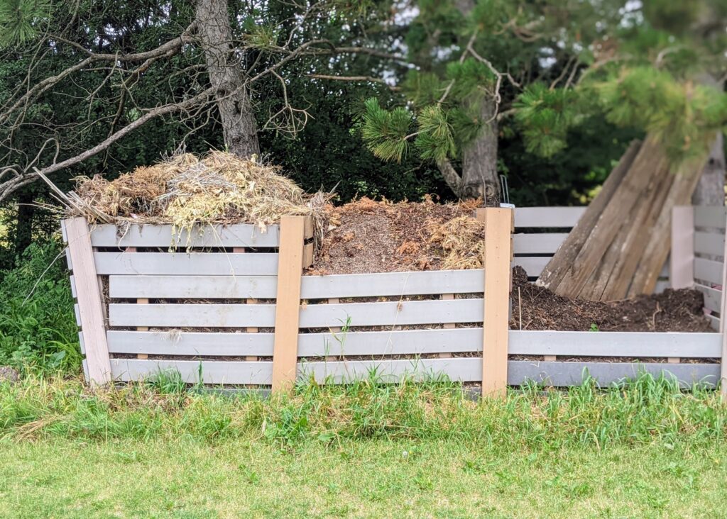 Three-bin compost system made of wood slats.