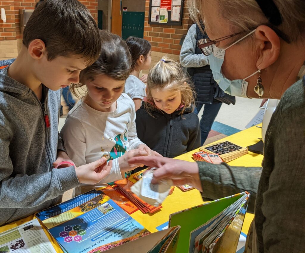 A volunteer educator talks with three young children about butterflies and flowers